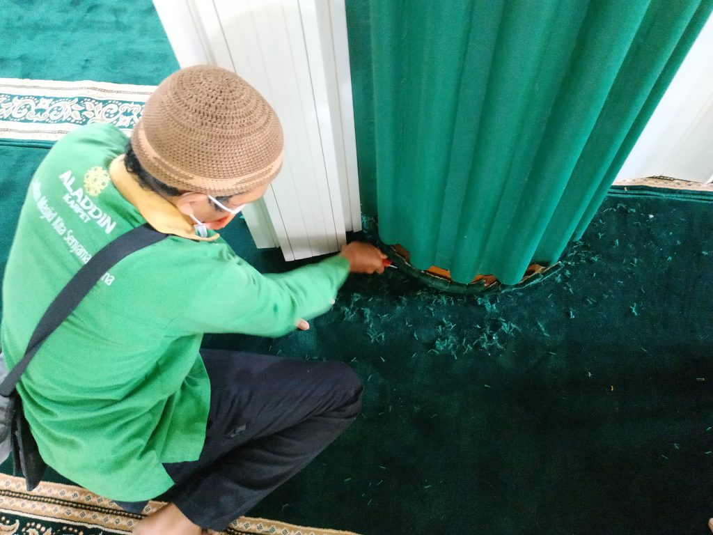proses pemasangan karpet masjid pada bagian bawah tiang masjid